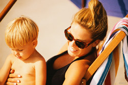 Smiling woman in a beach chair wearing sunglasses holding a young child
