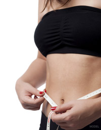 Woman's toned abdomen with tape measure around it