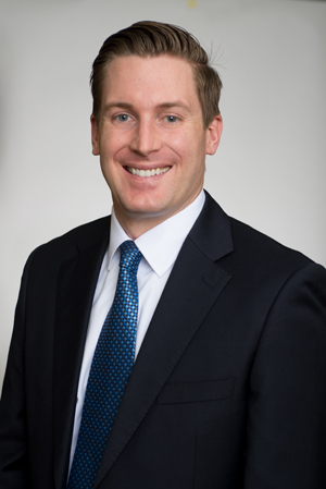 Dr. Corey Harkins in a dark suit and blue necktie