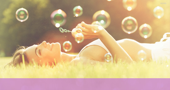 Woman lying in the grass blowing bubbles