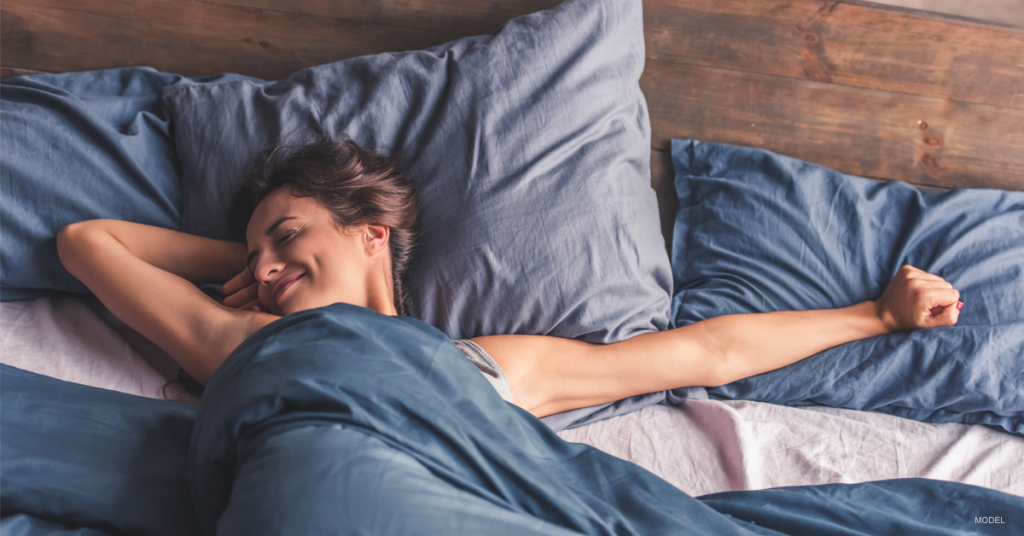 Woman stretching out her arms in bed and smiling