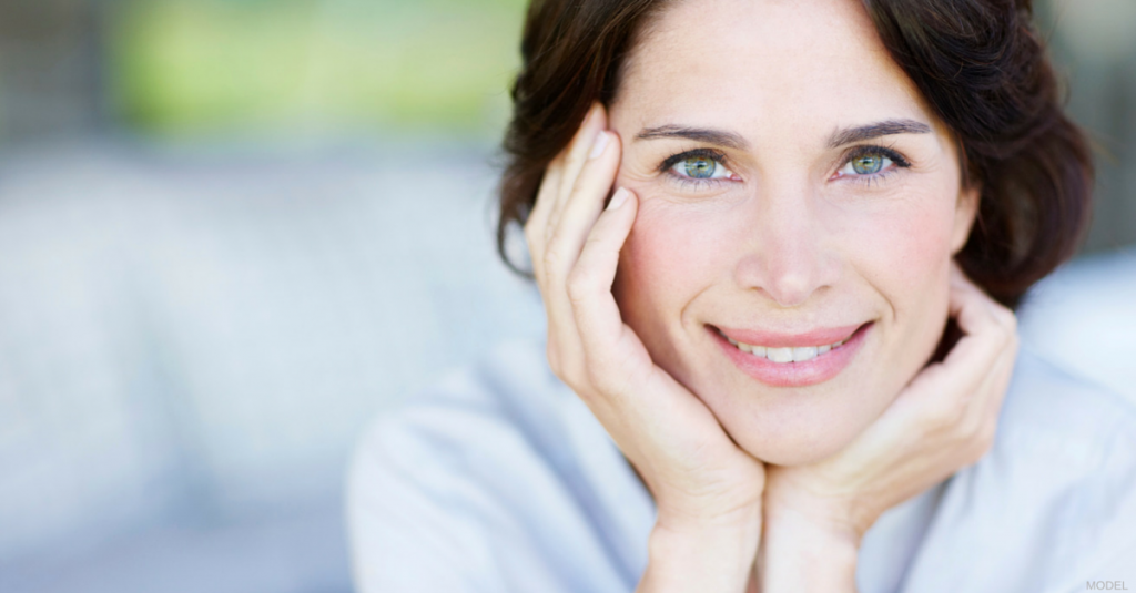 Woman smiling and holding her head up with her hands