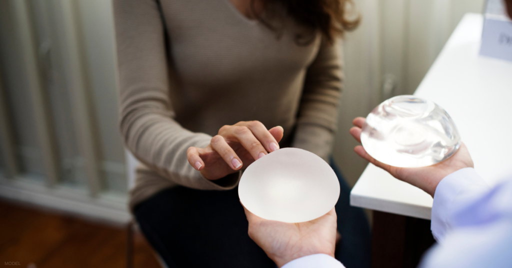 Woman and doctor comparing silicone vs. saline breast implants (models)