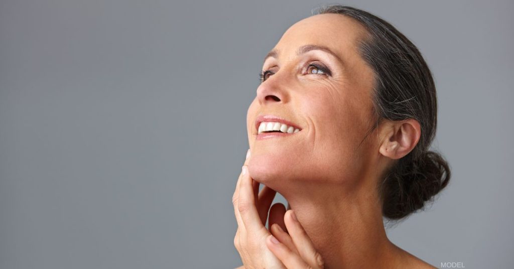 Woman with beautiful jawline touching her face and smiling (model)