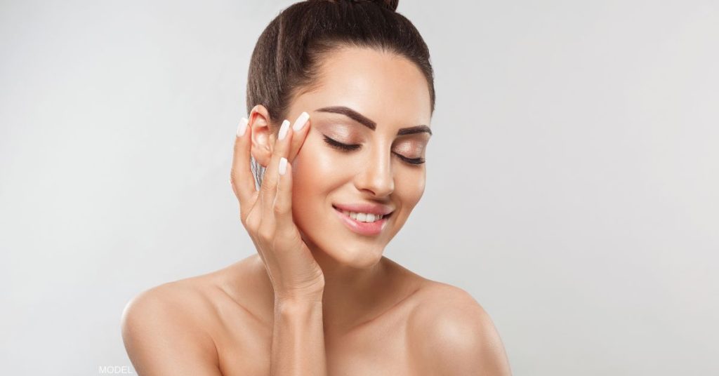 Beautiful woman smiling with her eyes closed touching her temple (model)